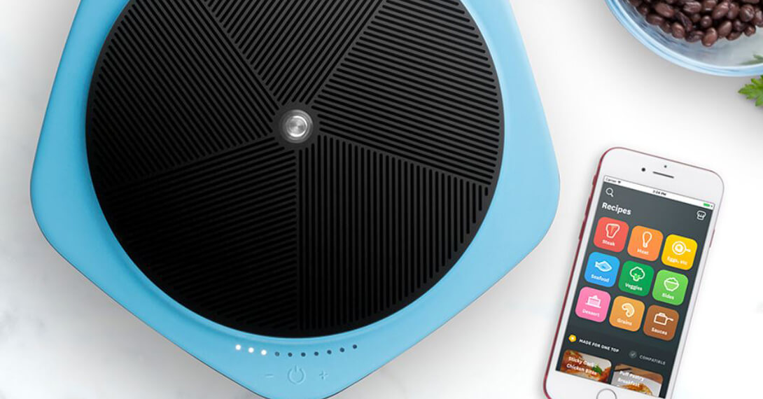 Blue Tasty One Top single-zone induction cooktop with a smartphone displaying a recipe interface beside the cooking surface